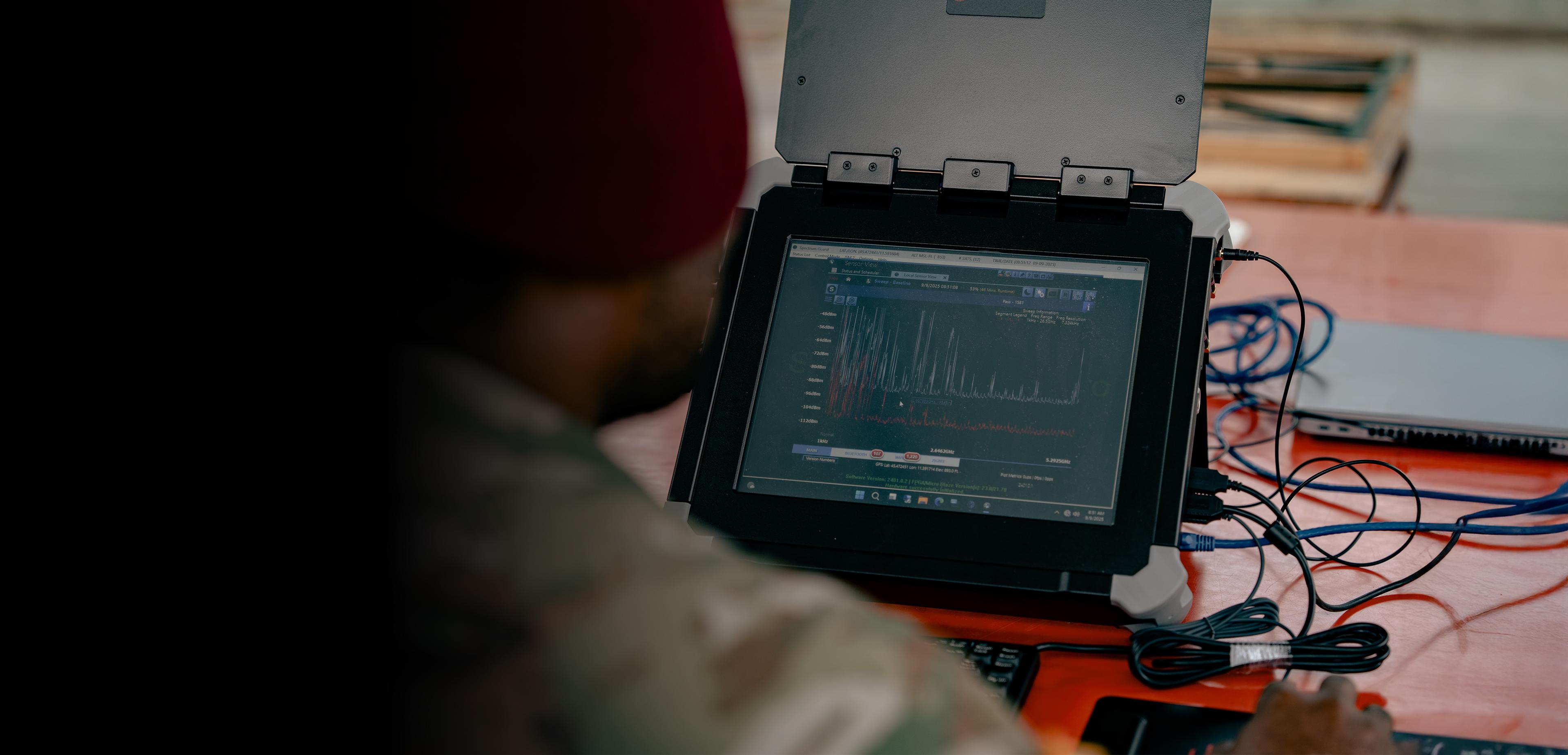 A soldier focused on a laptop computer, engaged in work or communication.