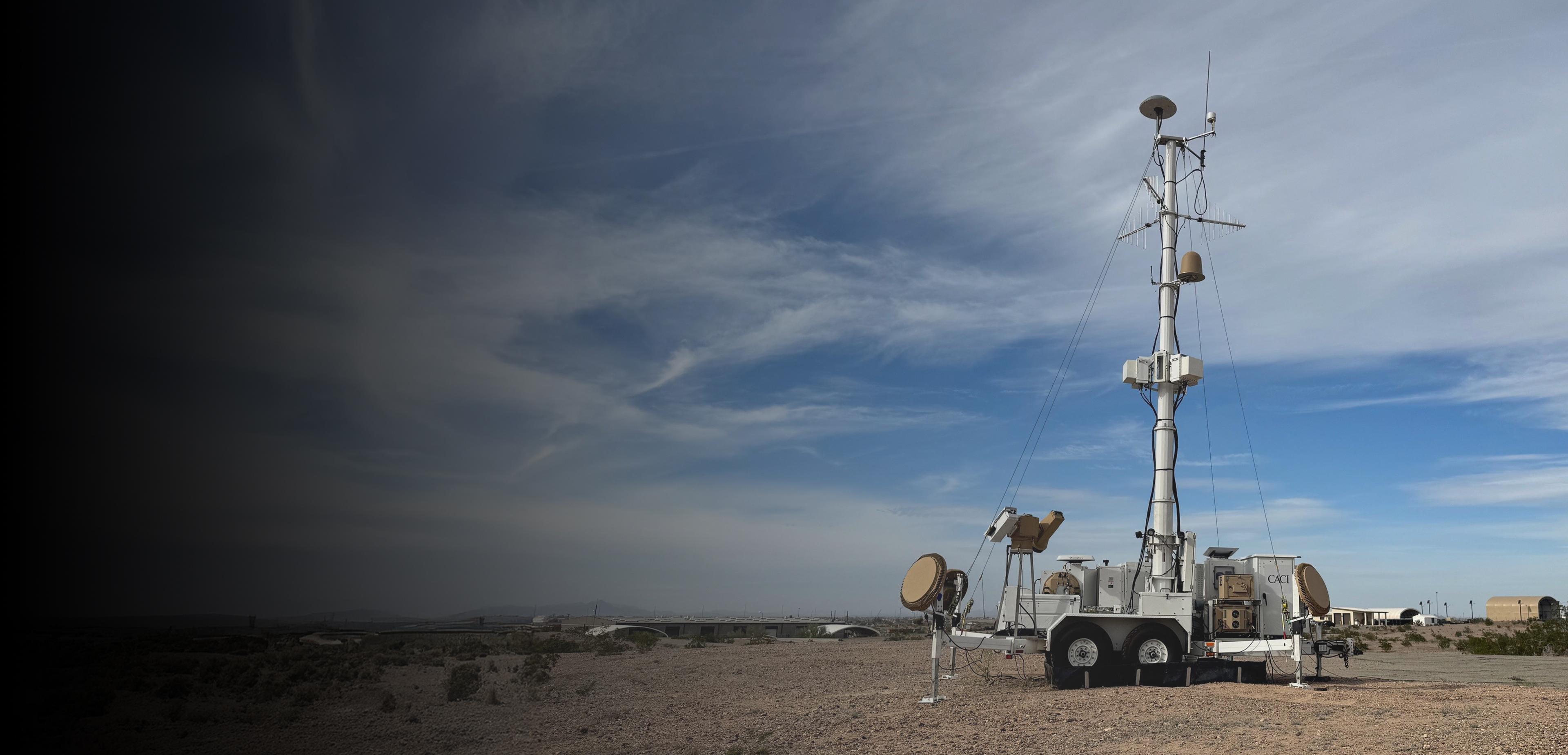 A tall metal tower with a satellite dish mounted at the top, set against a clear blue sky.