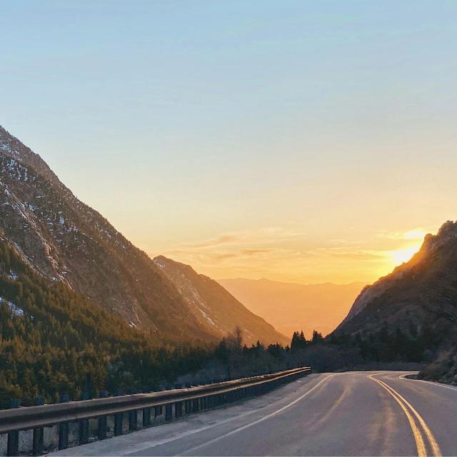 A road flowing through a mountain with a sunset background.