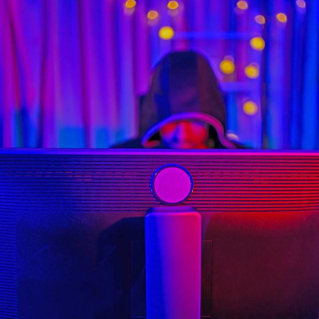 A hooded person working on a computer.