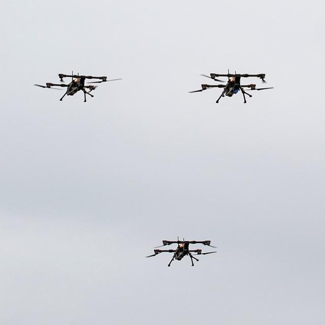 Three drones flying in a cloudy sky.