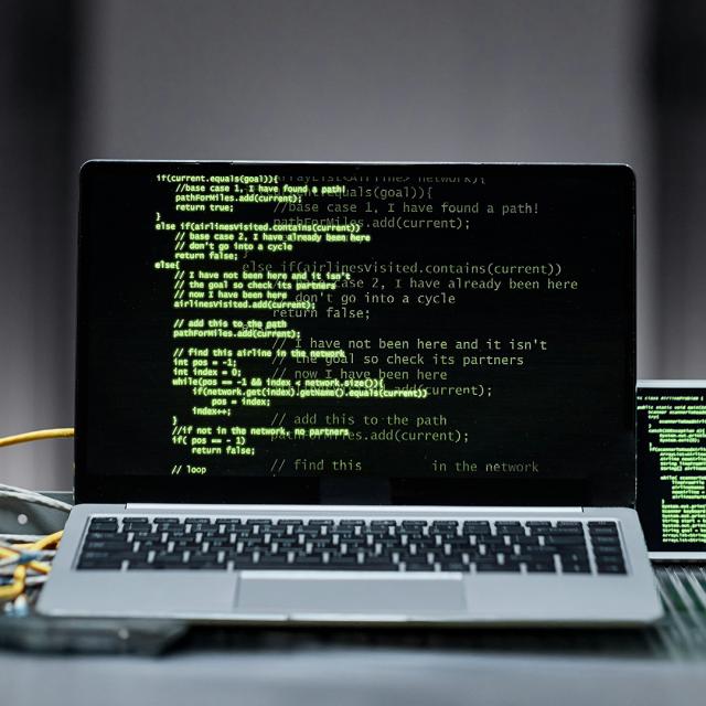 A laptop displaying a bright green screen, positioned on a wooden desk.
