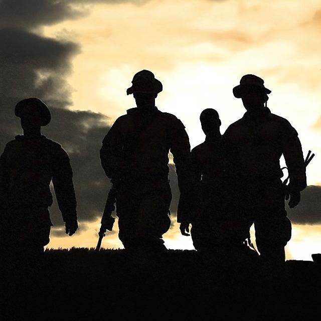 Silhouette of four soldiers walking together in a dark environment, conveying a sense of unity and purpose.