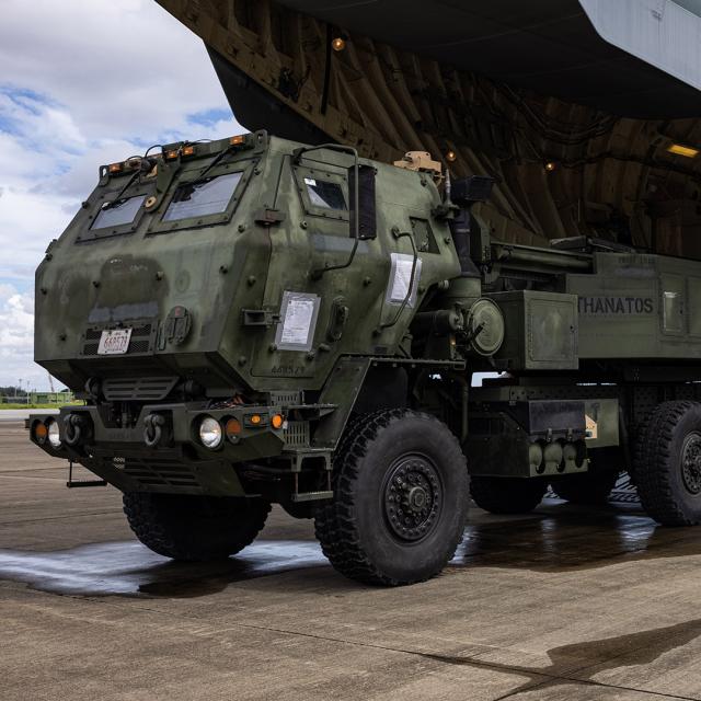A large military truck parked on a dirt road, showcasing its rugged design and camouflage paint.