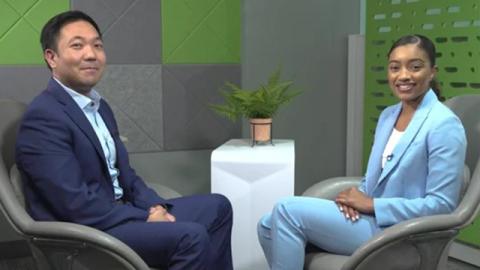 Two people in suits sit facing each other in modern chairs, smiling.