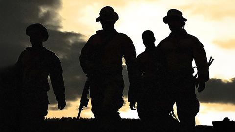 Silhouetted men stand against a vibrant sunset, creating a striking contrast between dark figures and colorful sky.