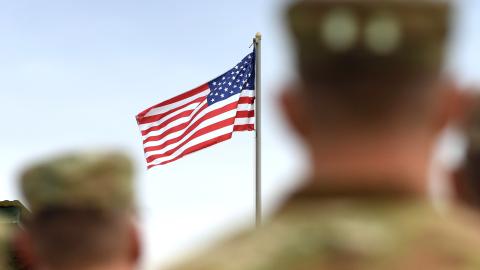 A group of soldiers stands proudly in front of an American flag, symbolizing patriotism and service.