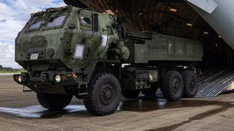 A large military truck parked on a dirt road, showcasing its rugged design and camouflage paint.