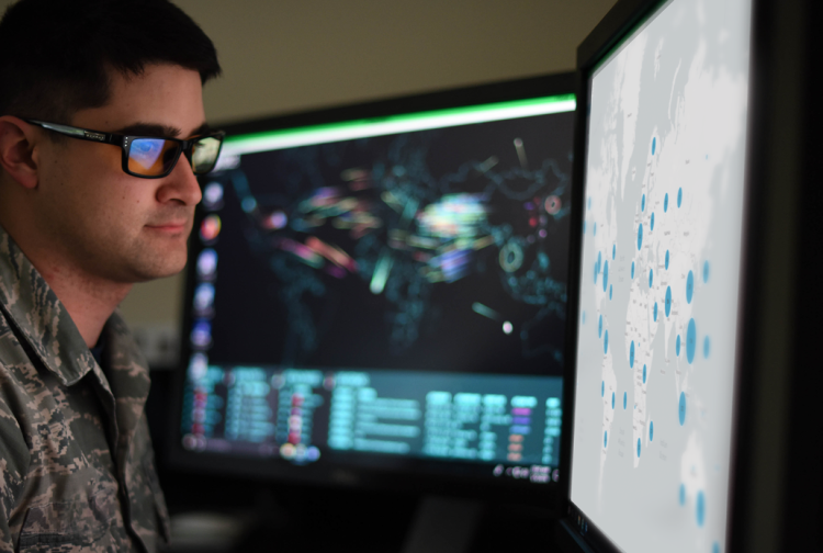 A soldier looking at data points on a map on a monitor.