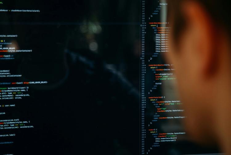 A man gazes at a computer screen filled with code, deeply engaged in his work on software development.
