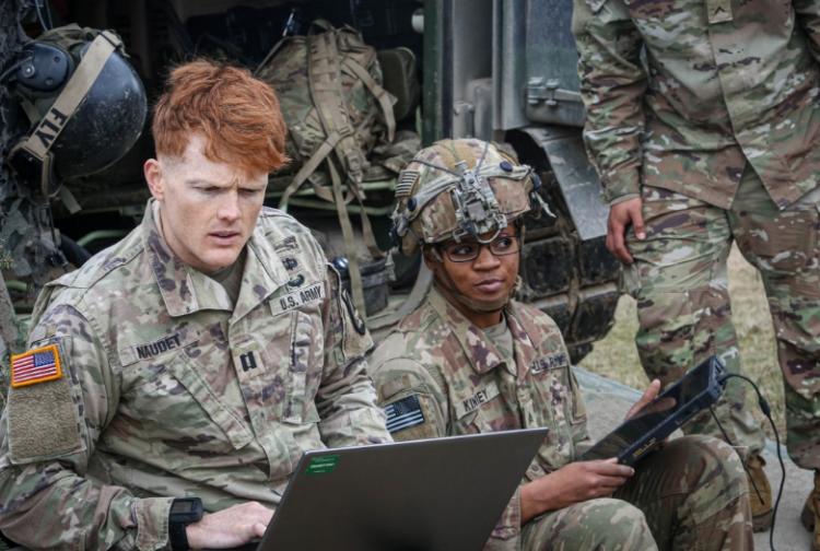 A soldier focused on a laptop computer, engaged in military operations or communication tasks.