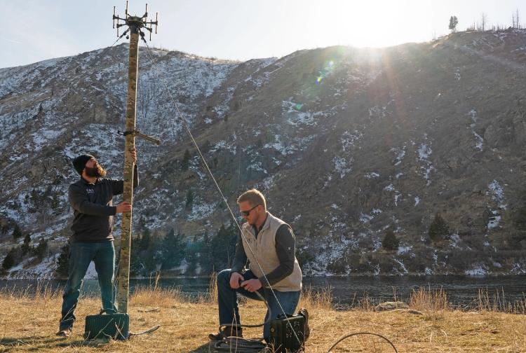 Two men stand together in front of a majestic mountain, showcasing the beauty of nature in the background.