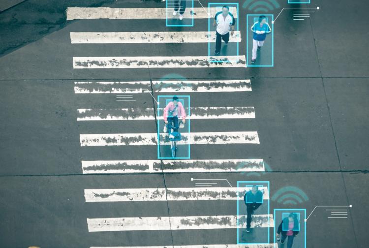 People crossing a street at a crosswalk while a traffic light signals for pedestrians to walk.