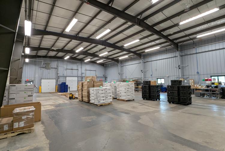 A spacious warehouse filled with stacked boxes and pallets arranged in the center, showcasing an organized storage area.
